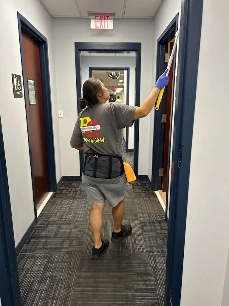 Rivera team member wiping a doorframe in an office hallway