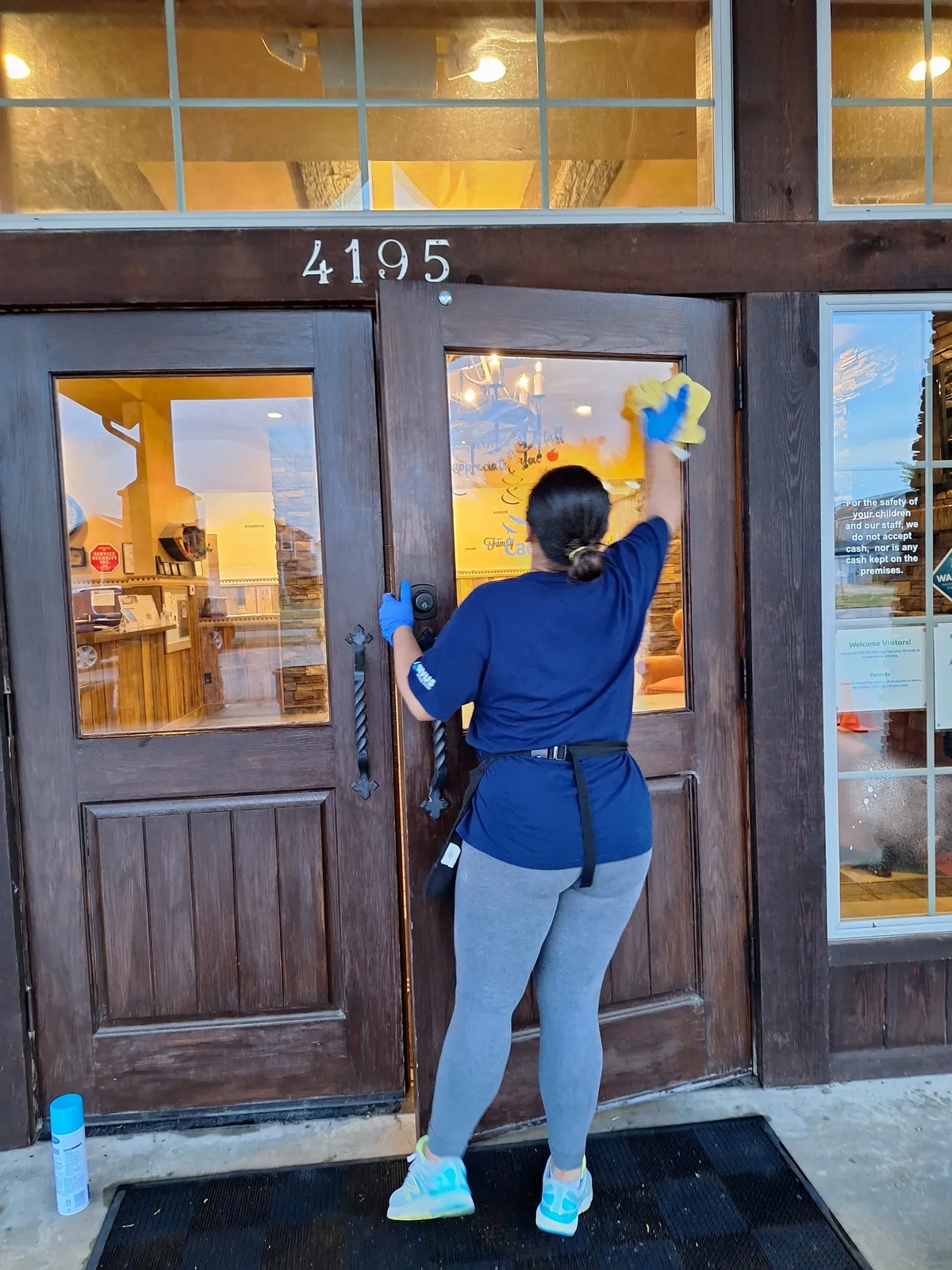 Rivera team member carefully wiping a glass entrance door with a yellow cloth