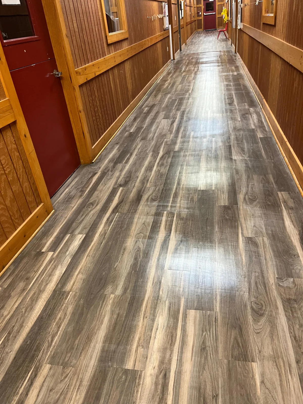 Clean wood-look flooring in a wood-paneled hallway