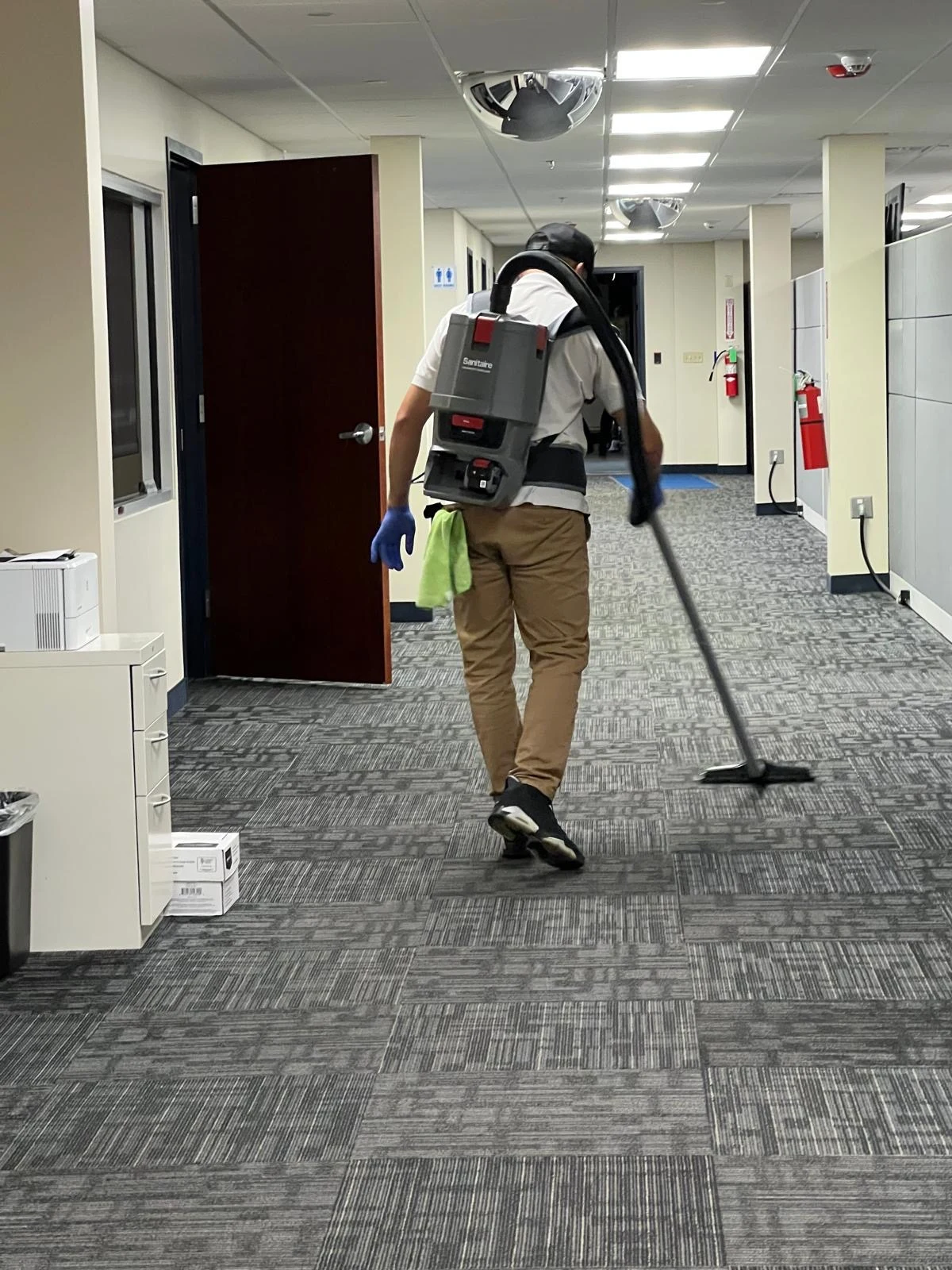Rivera team member vacuuming a carpeted office hallway